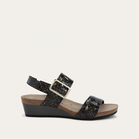 Profile view of a black wedge sandal with a snakeskin design, featuring two straps and a metallic buckle with a cork footbed.