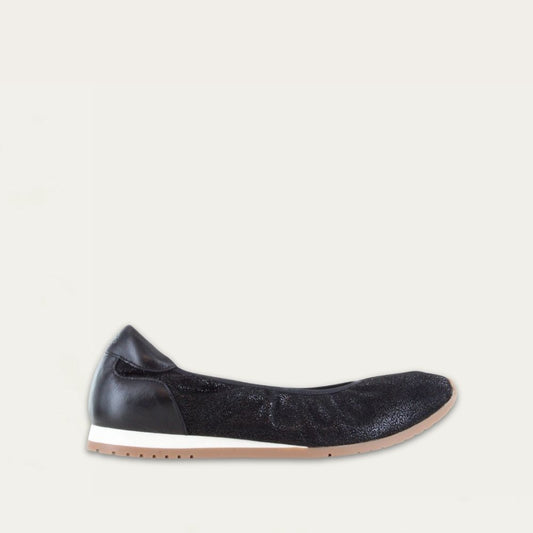 Profile view of a textured black suede flat on a low white and beige sole. 