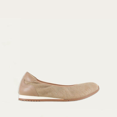 Profile view of a textured beige suede flat on a low white and beige sole. 