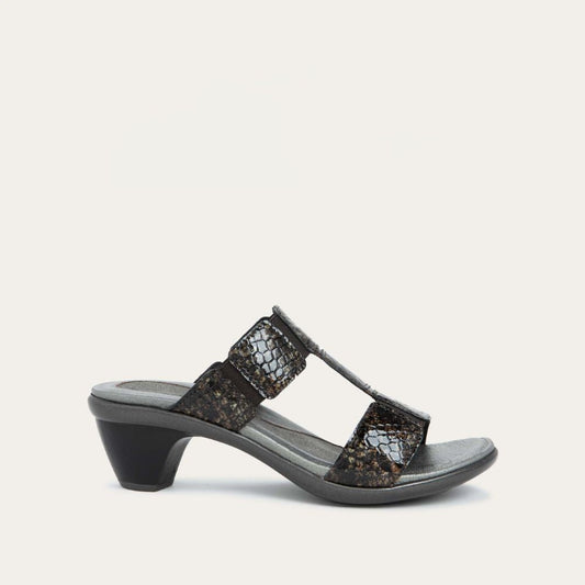 Profile view of a slip-on t-strap reptile printed sandal with a mid-height heel .