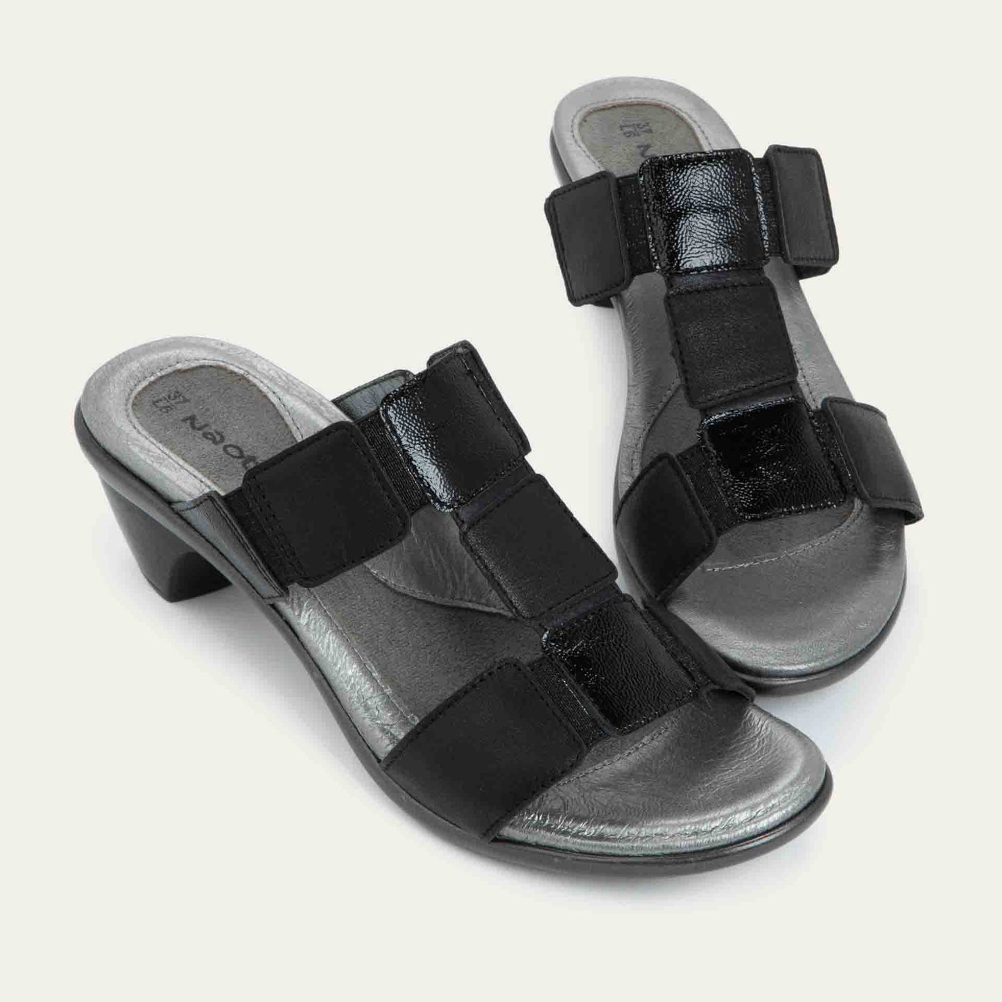 A pair of slip-on t-strap black sandals with a mid-height heel .