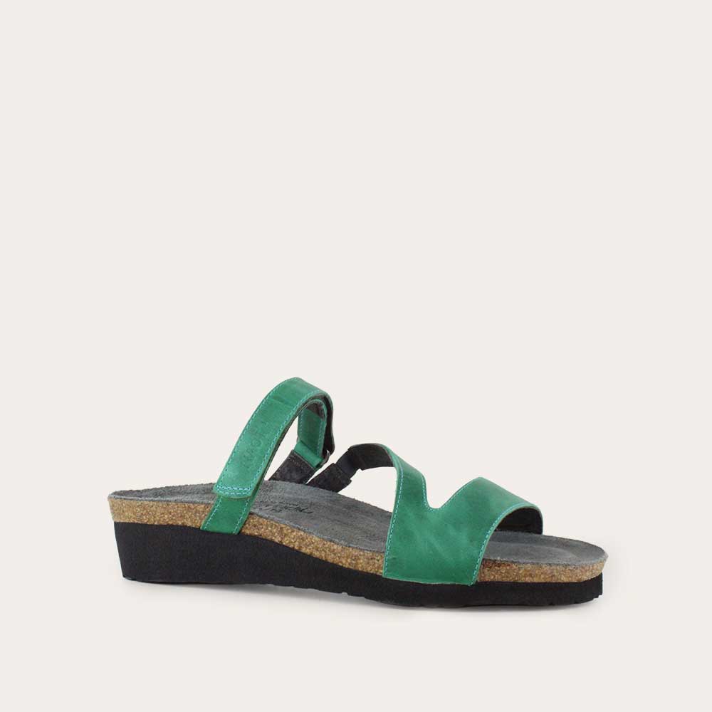 Angled profile view of a green slip-on wedge sandal with a cork insole on a black sole.