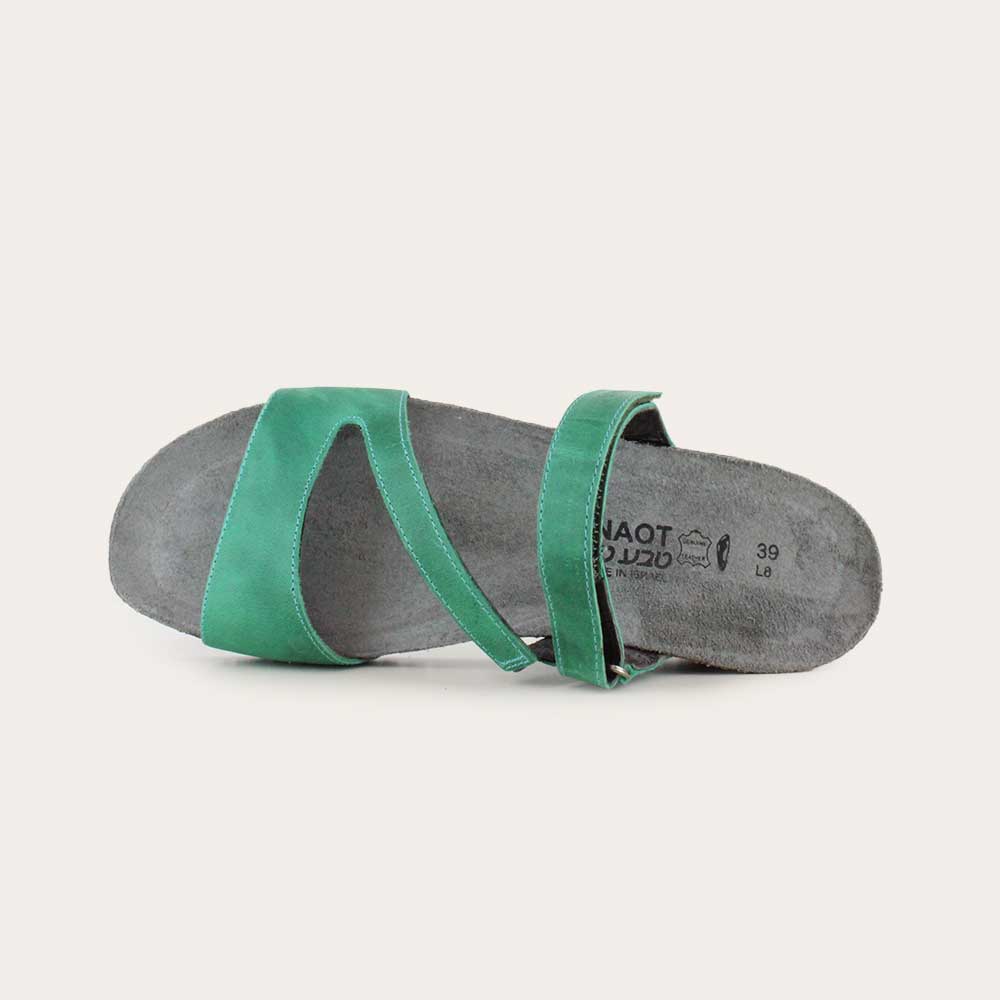 Top view view of a green slip-on wedge sandal with a cork insole on a black sole.