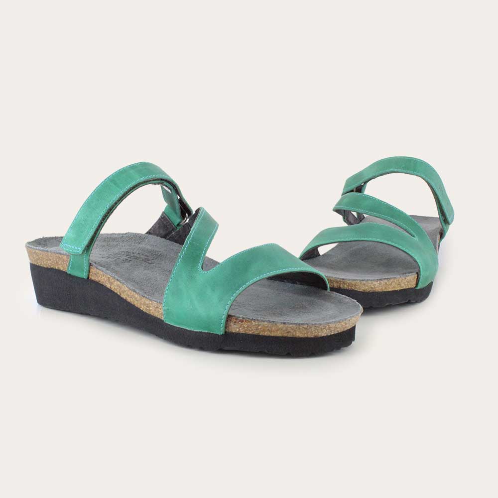 Pair of  green slip-on wedge sandals with a cork insole on a black sole.