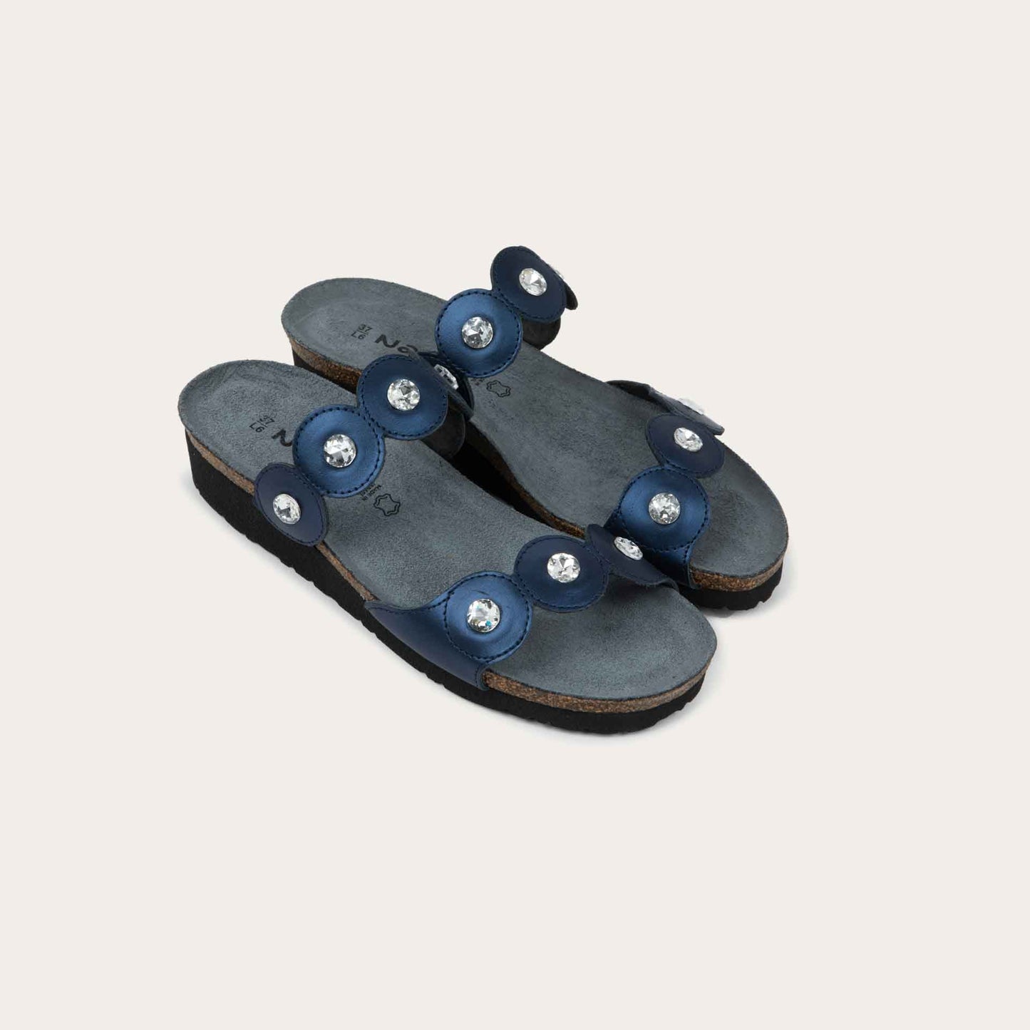 Pair of navy blue sandals with cork wedge sole. Features two straps with circular details and large round silver studs.