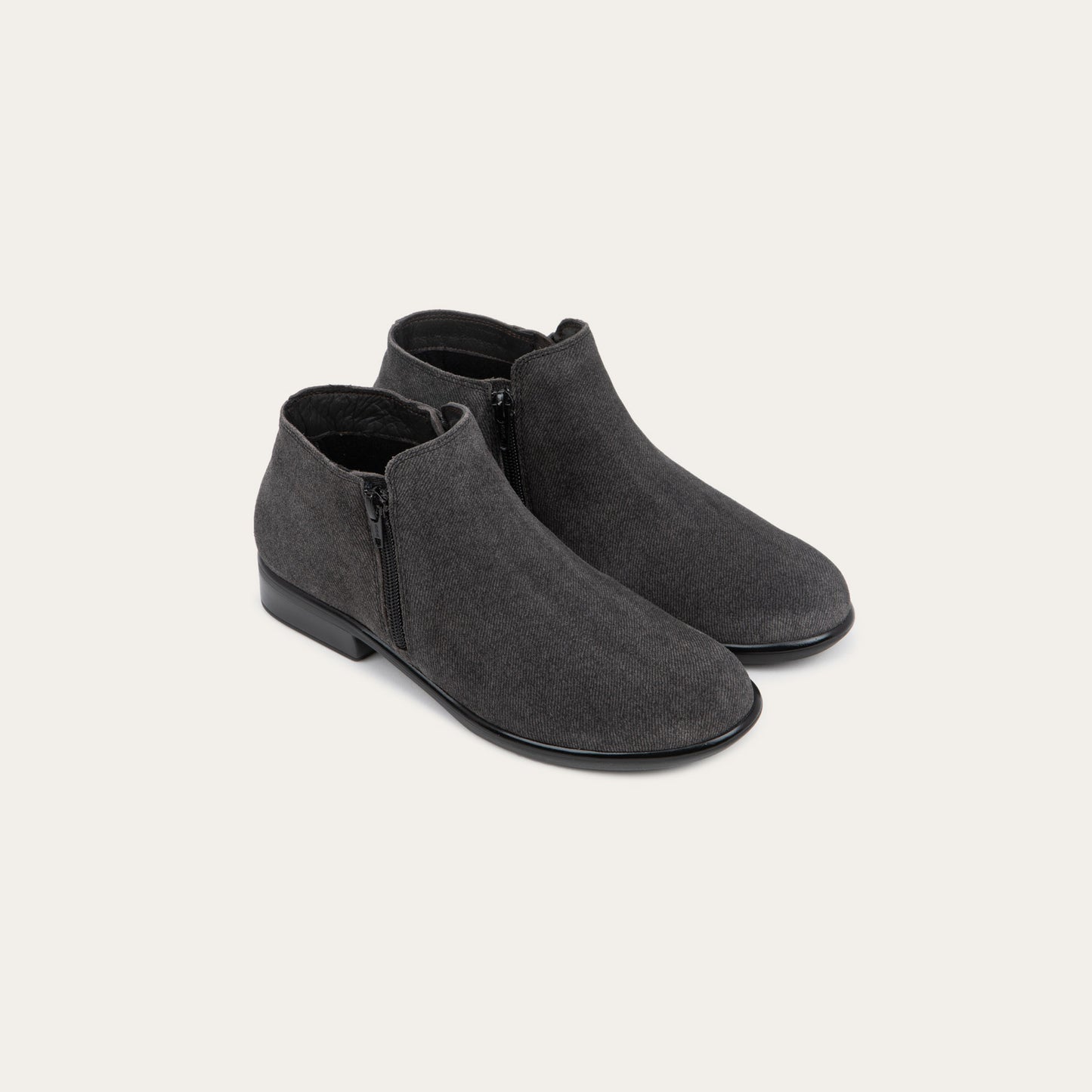 A pair of black suede booties on a black and brown sole.
