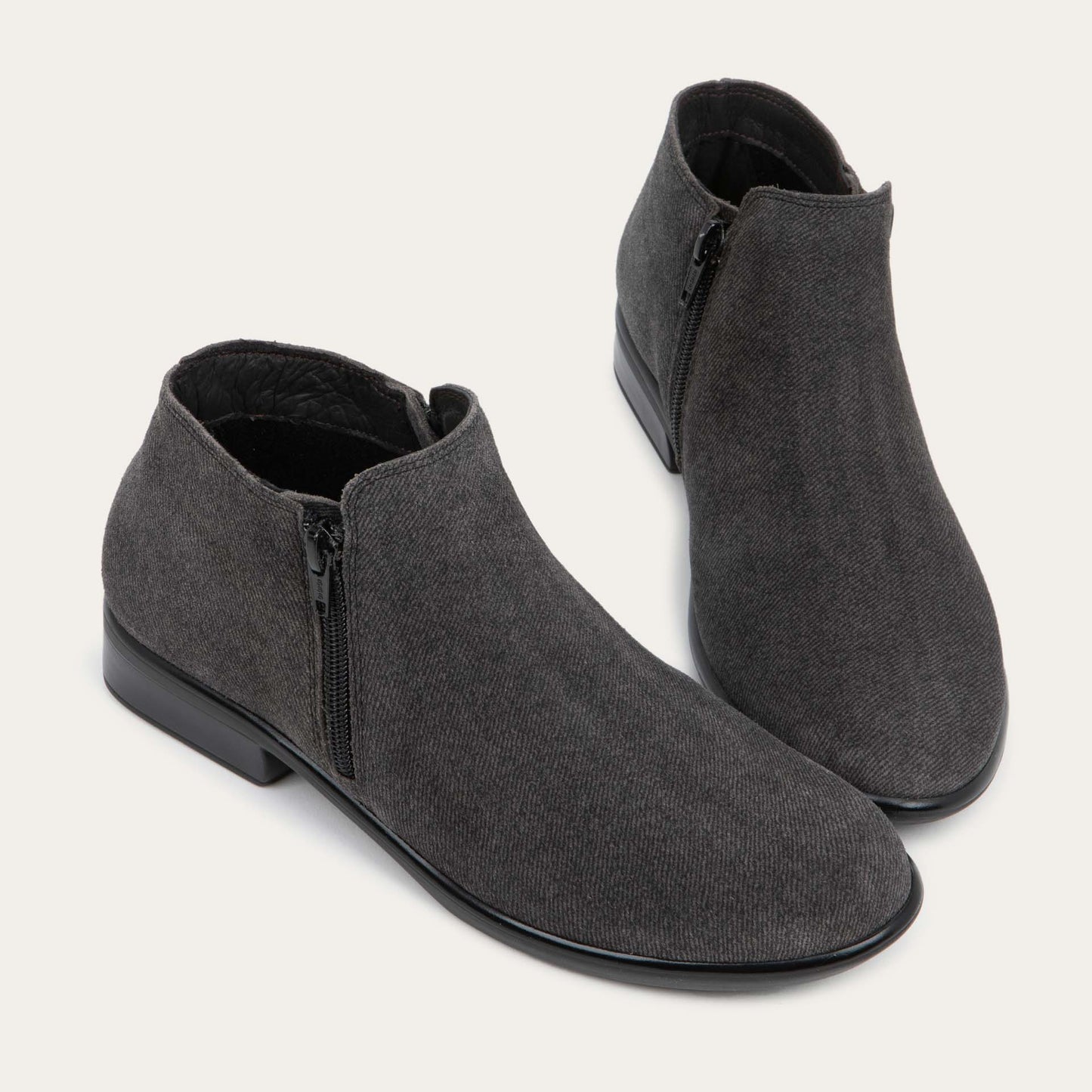 A pair of black suede booties on a black and brown sole.