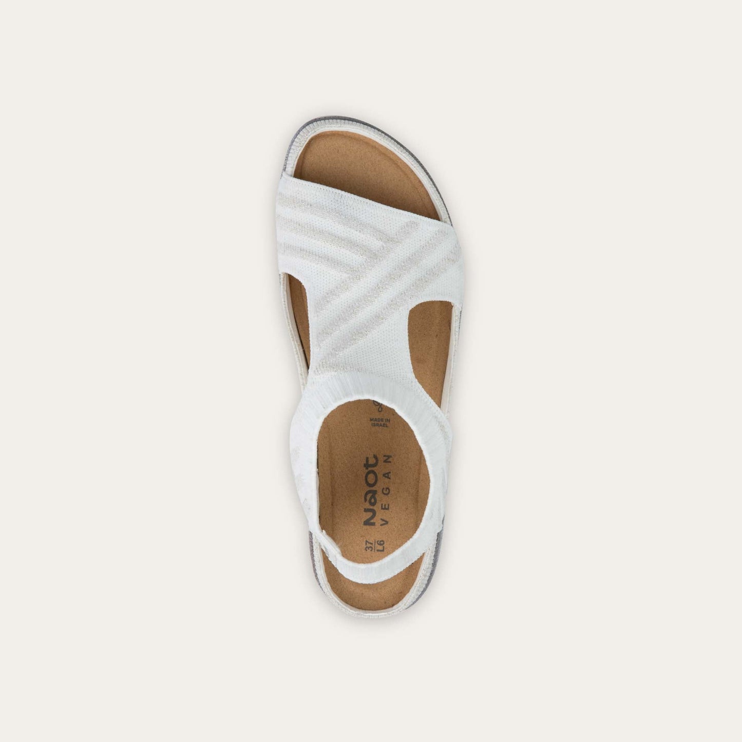 Top view of a white sparkle knit cutout sandal with open toes, elastic ankle strap, and black textured sole.