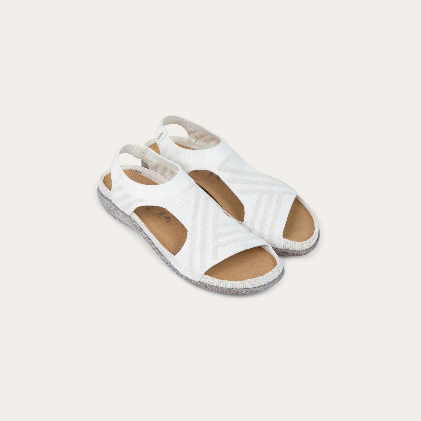Pair of white sparkle knit cutout sandals with open toes, elastic ankle strap, and black textured sole.