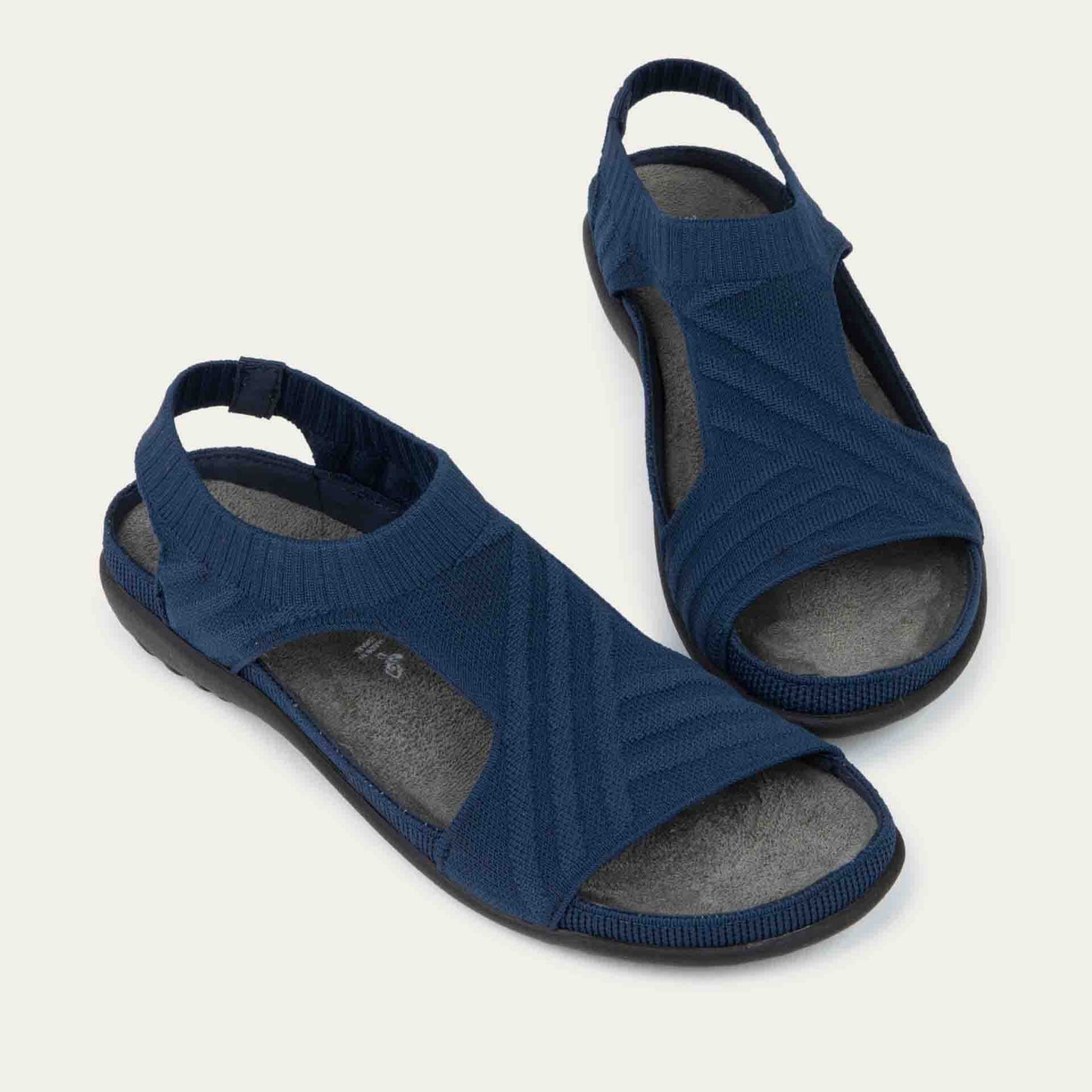 Pair of navy knit cutout sandals with open toes, elastic ankle strap, and black textured sole.