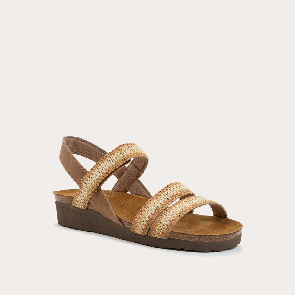 Angled profile view of  brown and ivory raffia sandal with a cork footbed, black sole, and triple-strap design including a crisscross ankle strap.