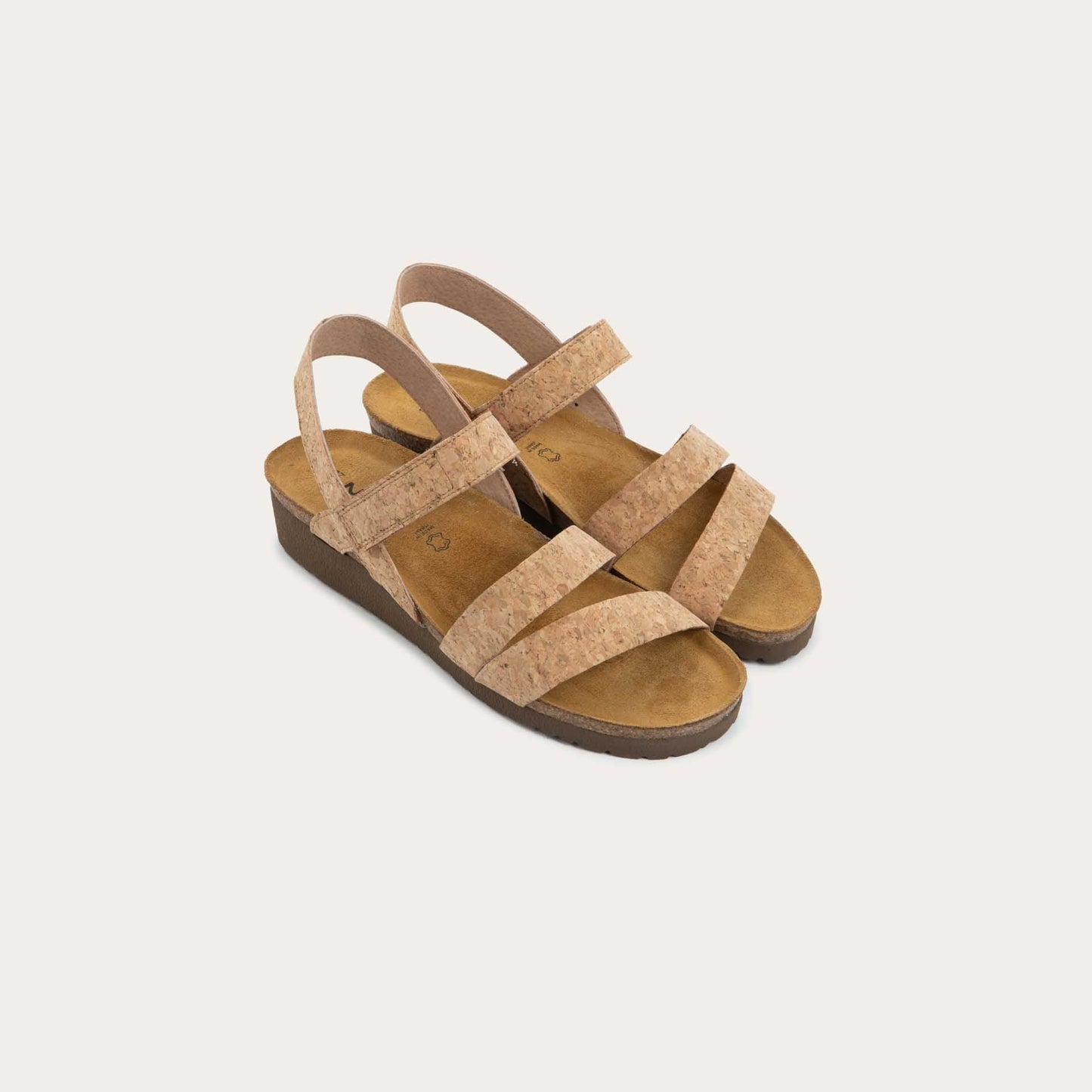 Profile view of cork-leather sandals with a cork footbed, black sole, and triple-strap design including a crisscross ankle strap.