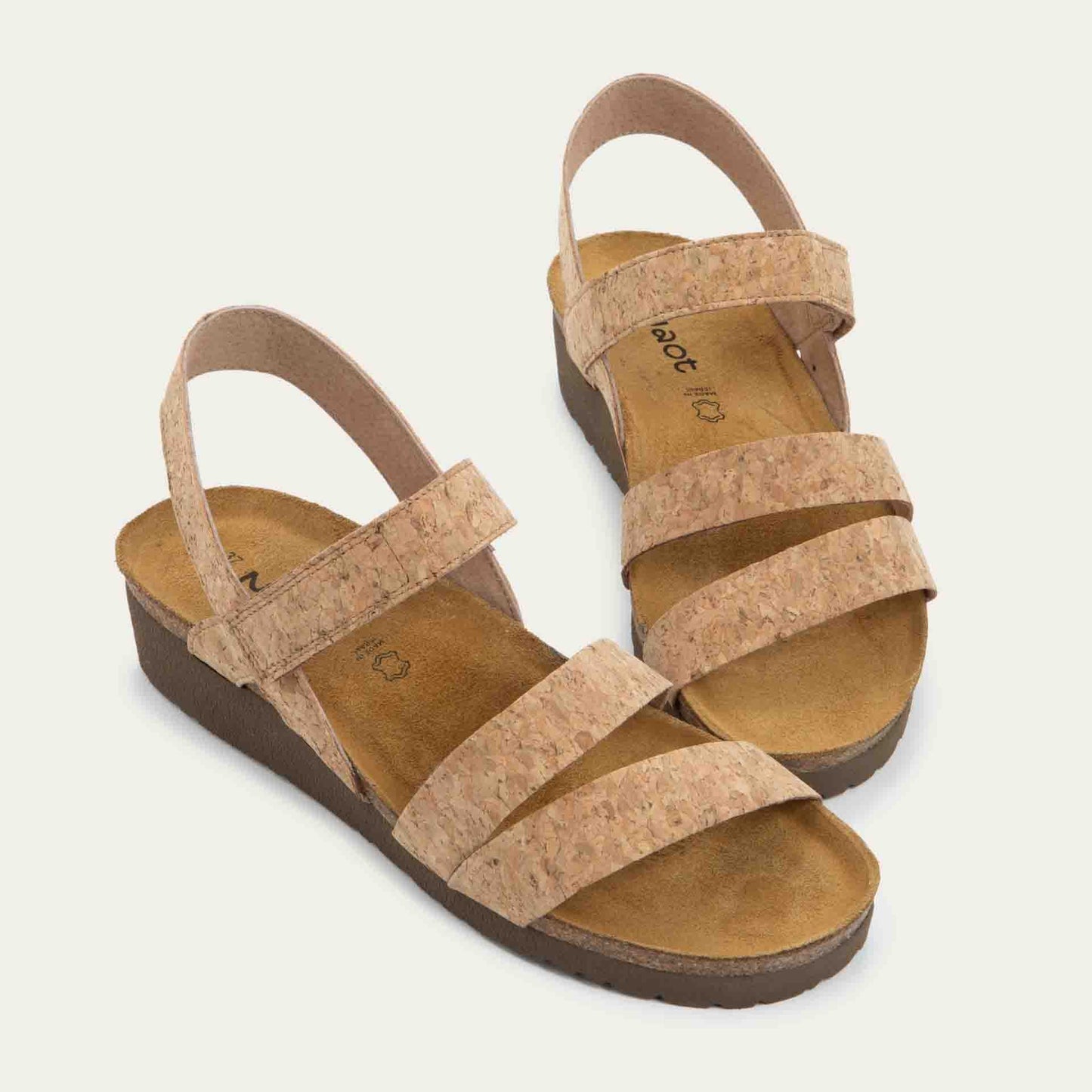 Profile view of cork-leather sandals with a cork footbed, black sole, and triple-strap design including a crisscross ankle strap.