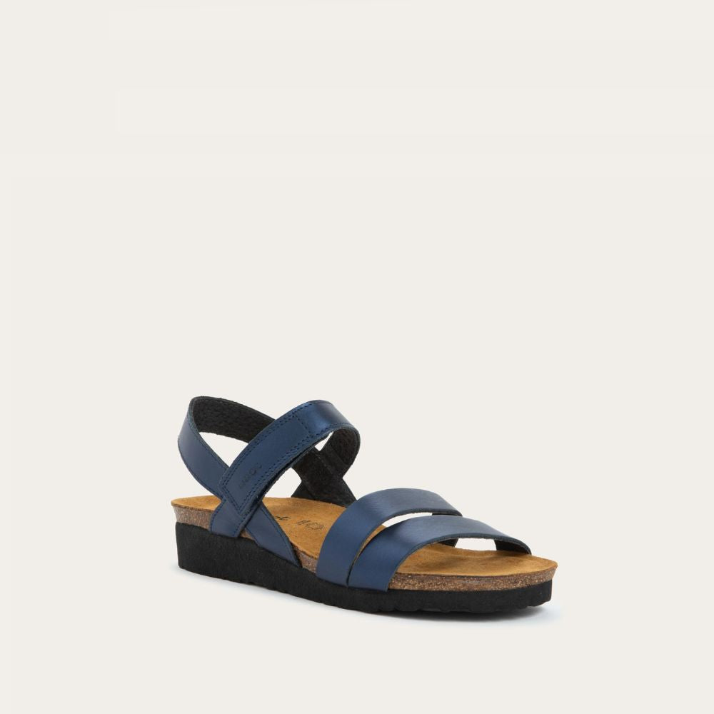 Angled profile view of a navy blue sandal with a cork footbed, black sole, and triple-strap design including a crisscross ankle strap.
