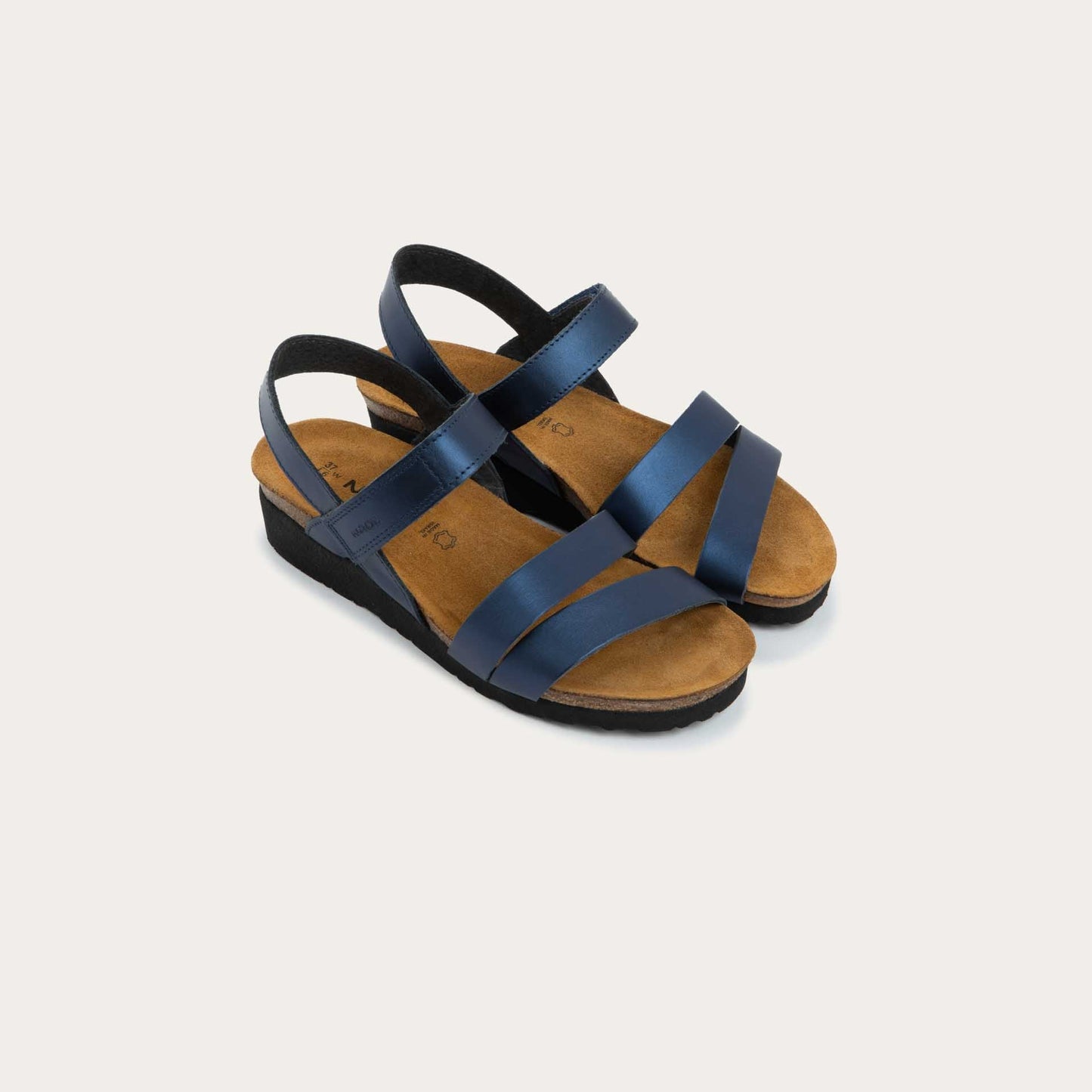 Pair of  navy blue sandals with a cork footbed, black sole, and triple-strap design including a crisscross ankle strap.
