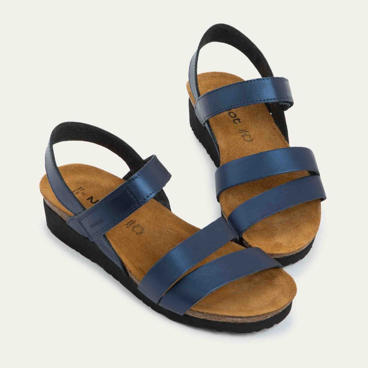 Pair of  navy blue sandals with a cork footbed, black sole, and triple-strap design including a crisscross ankle strap.