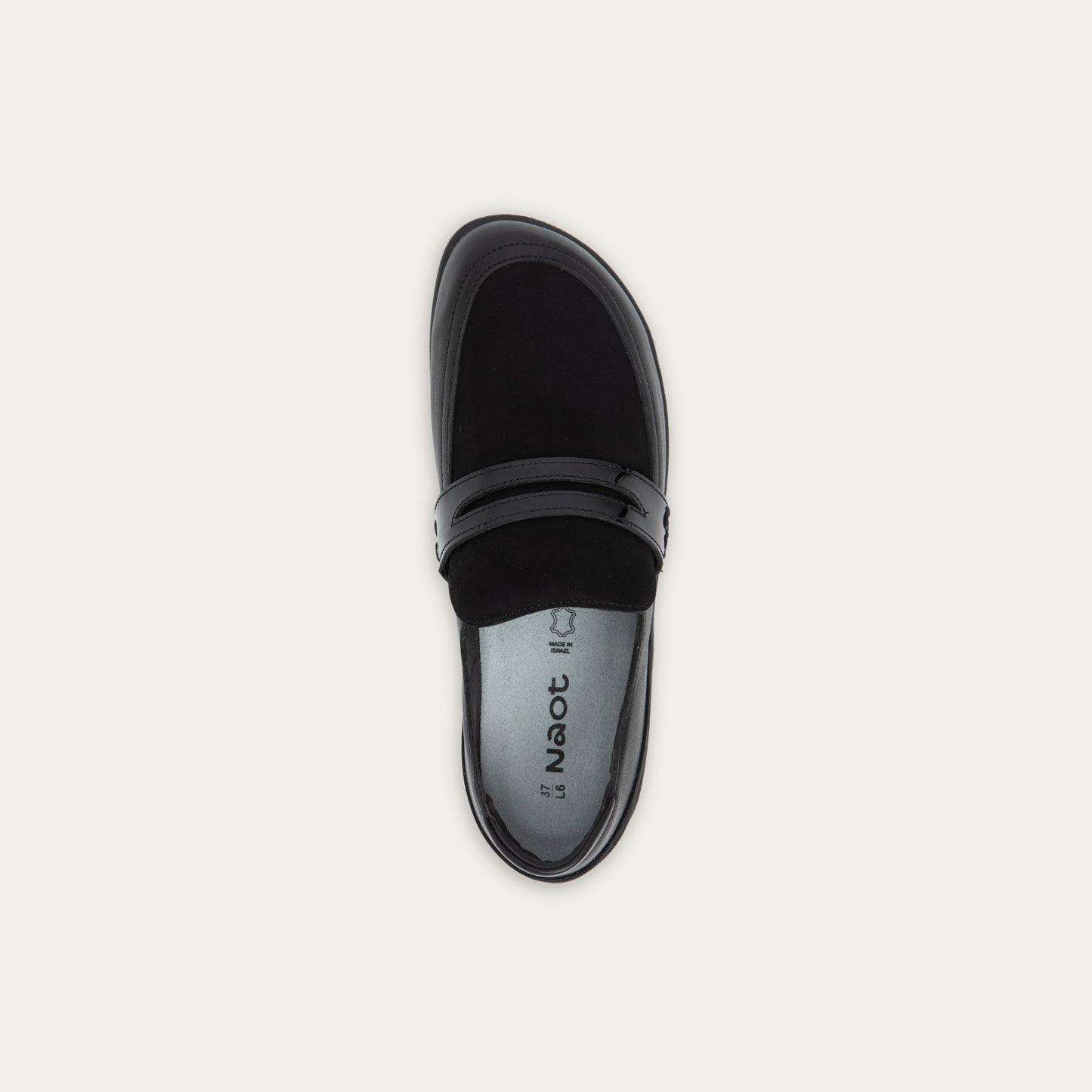 Top view of a black slip-on loafer featuring a mix of matte leather and soft suede textures with a glossy patent leather strap across the vamp.