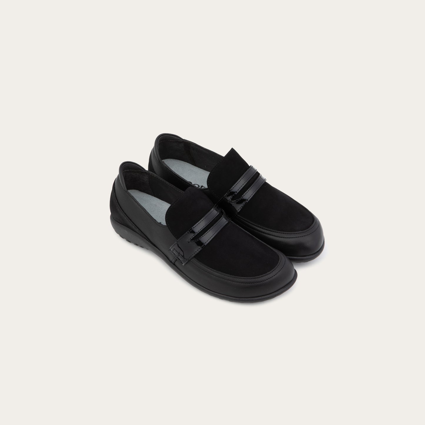 Pair of black slip-on loafers featuring a mix of matte leather and soft suede textures with a glossy patent leather straps across the vamp.
