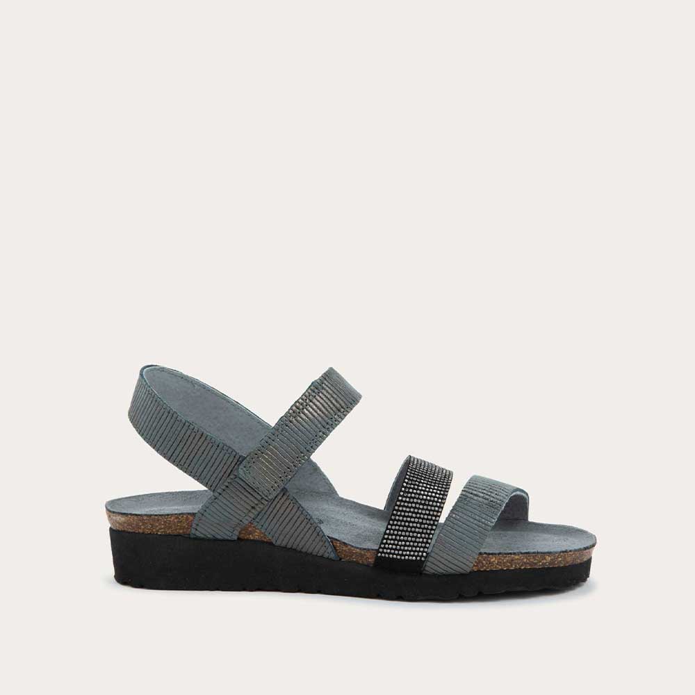 Profile view of a gray sandal with two textured straps and a studded strap on a cork and black rubber sole,
