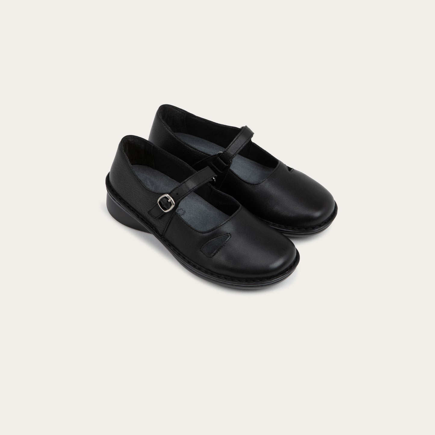 Pair of  black maryjanes on a black sole featuring a simple buckle and small cutout detail on the side
