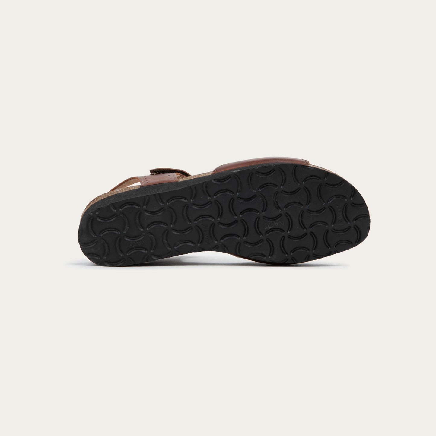 Bottom view of a brown sandal featuring a toe strap with contrast stitiching, adjustable ankle strap, and a cork footbed.