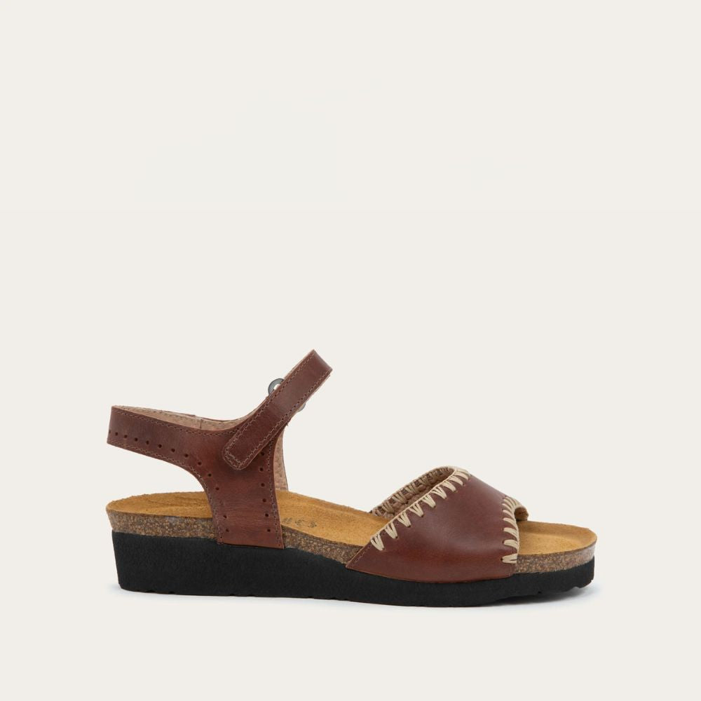 Profile view of black and brown raffia sandal with a cork footbed, black sole, and triple-strap design including a crisscross ankle strap.