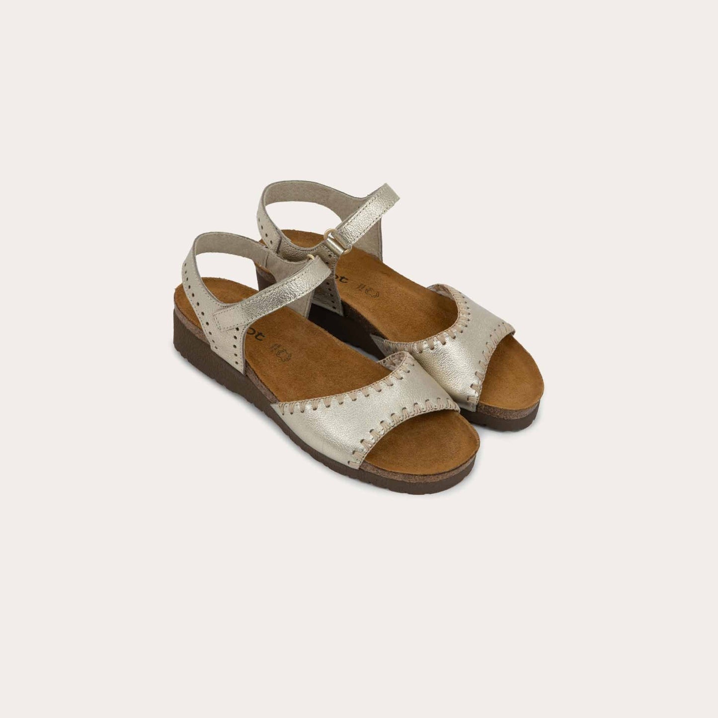 Pair of gold sandals featuring a toe strap with contrast stitiching, adjustable ankle strap, and a cork footbed.