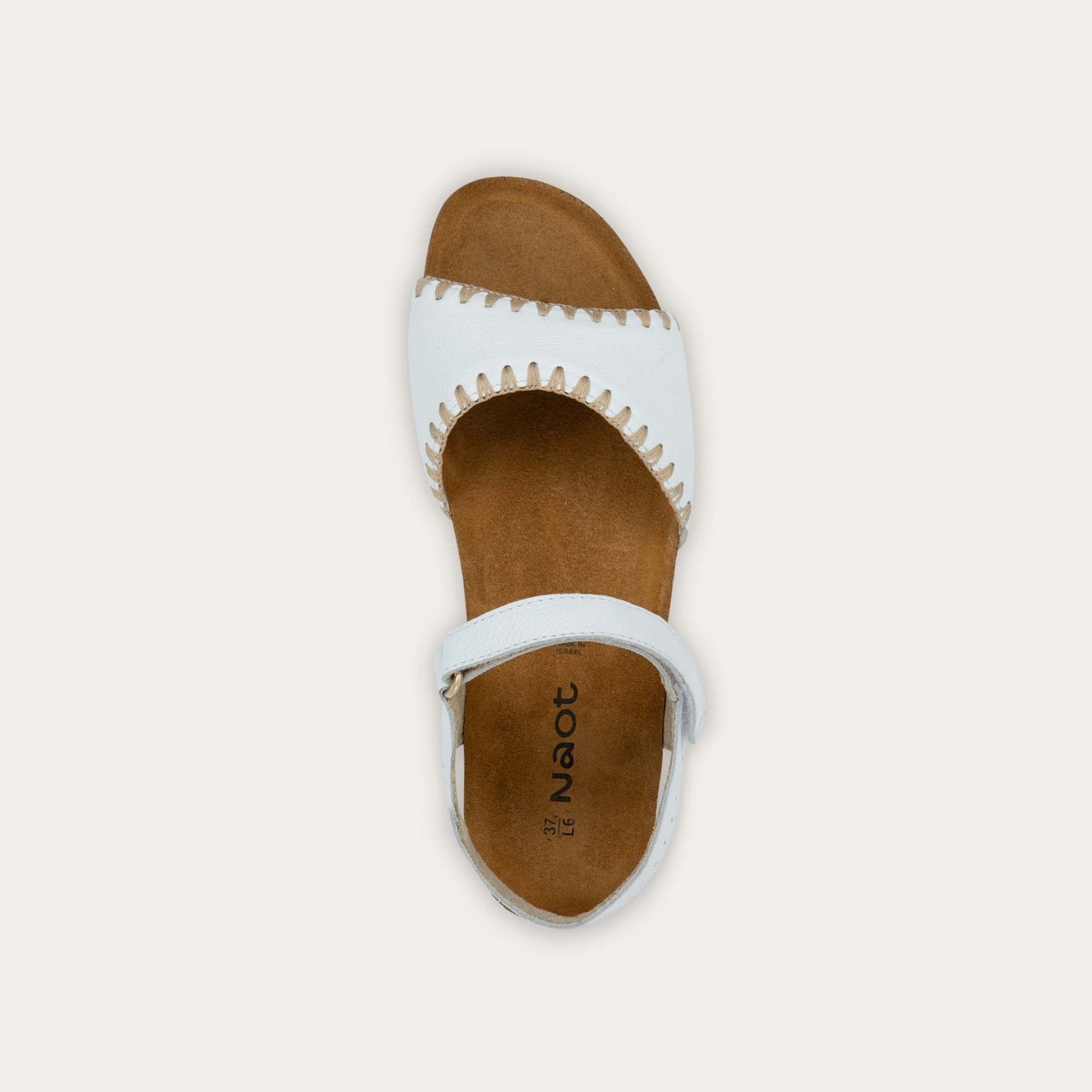 Top view of a white sandal featuring a toe strap with contrast stitiching, adjustable ankle strap, and a cork footbed.