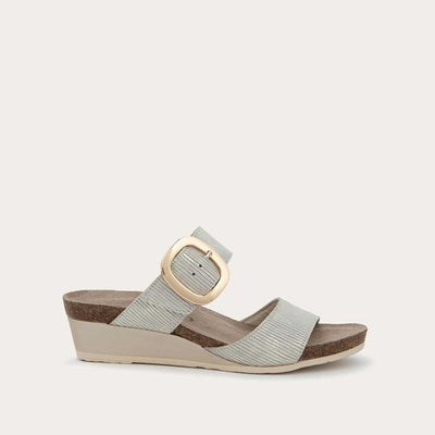 Profile view of a metallic gray textured wedge sandal with two straps and a large gold buckle. 