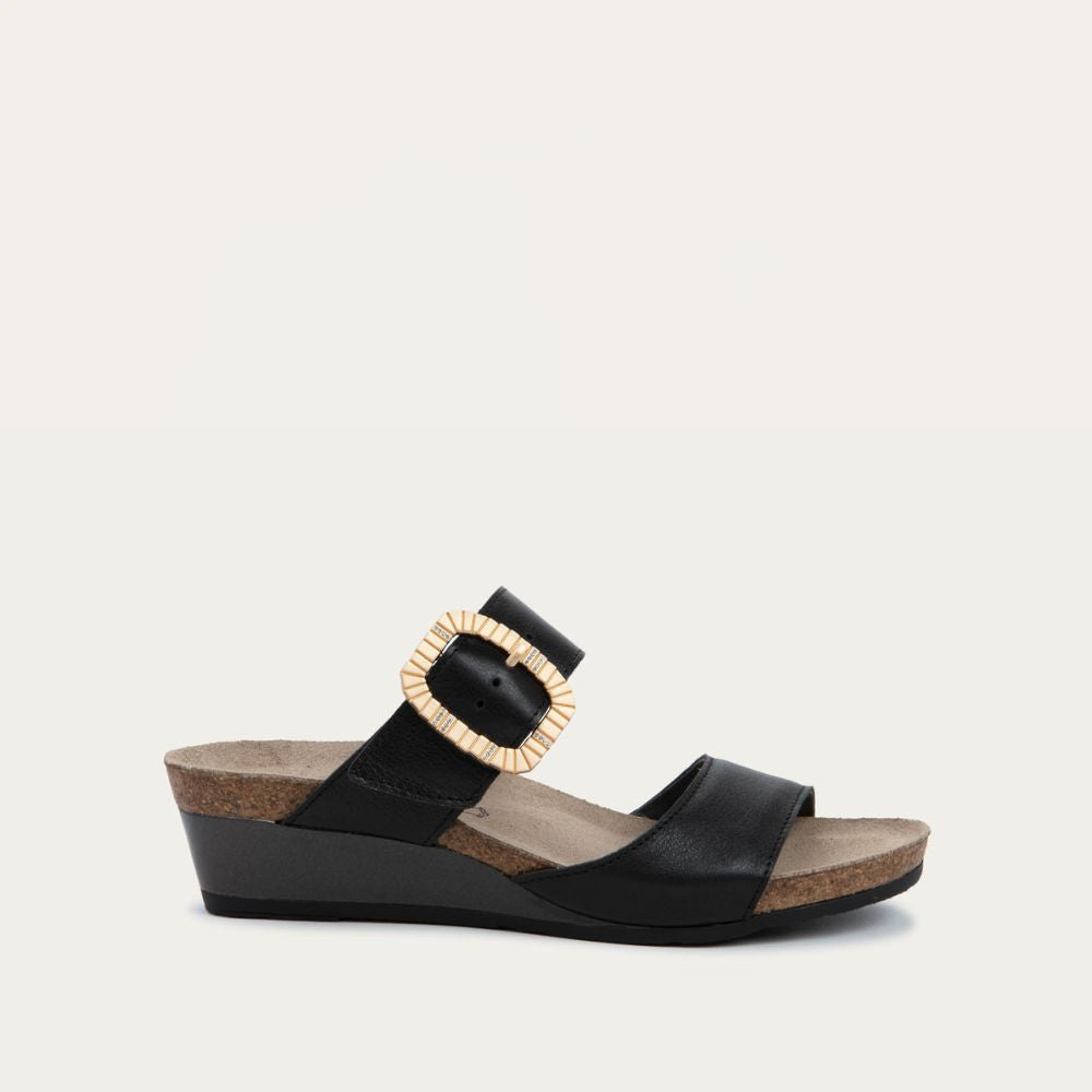 Profile view of a black slip-on wedge sandal with two straps and a large textured buckle. 