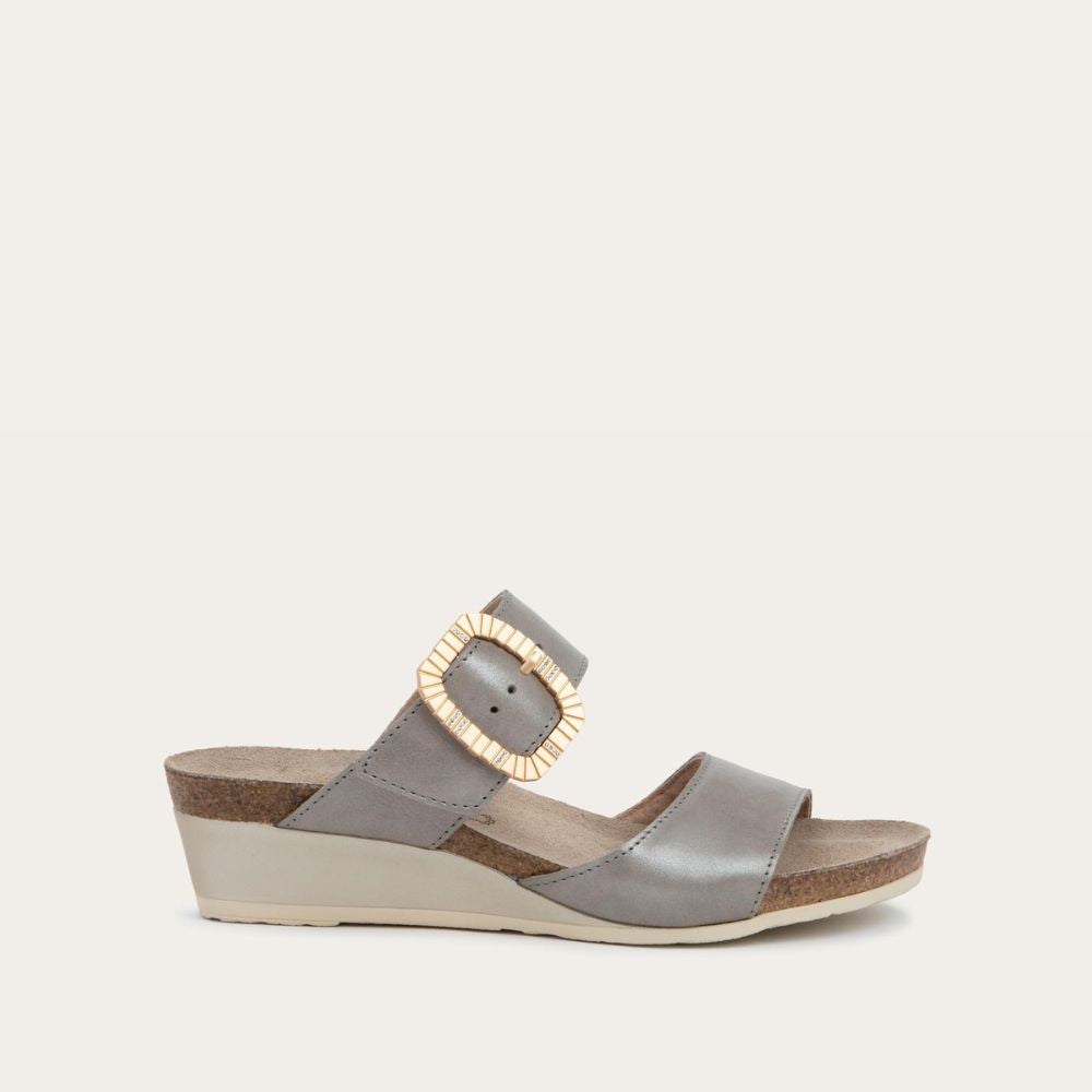 Profile view of a metalic gray slip-on wedge sandal with two straps and a large textured buckle. 