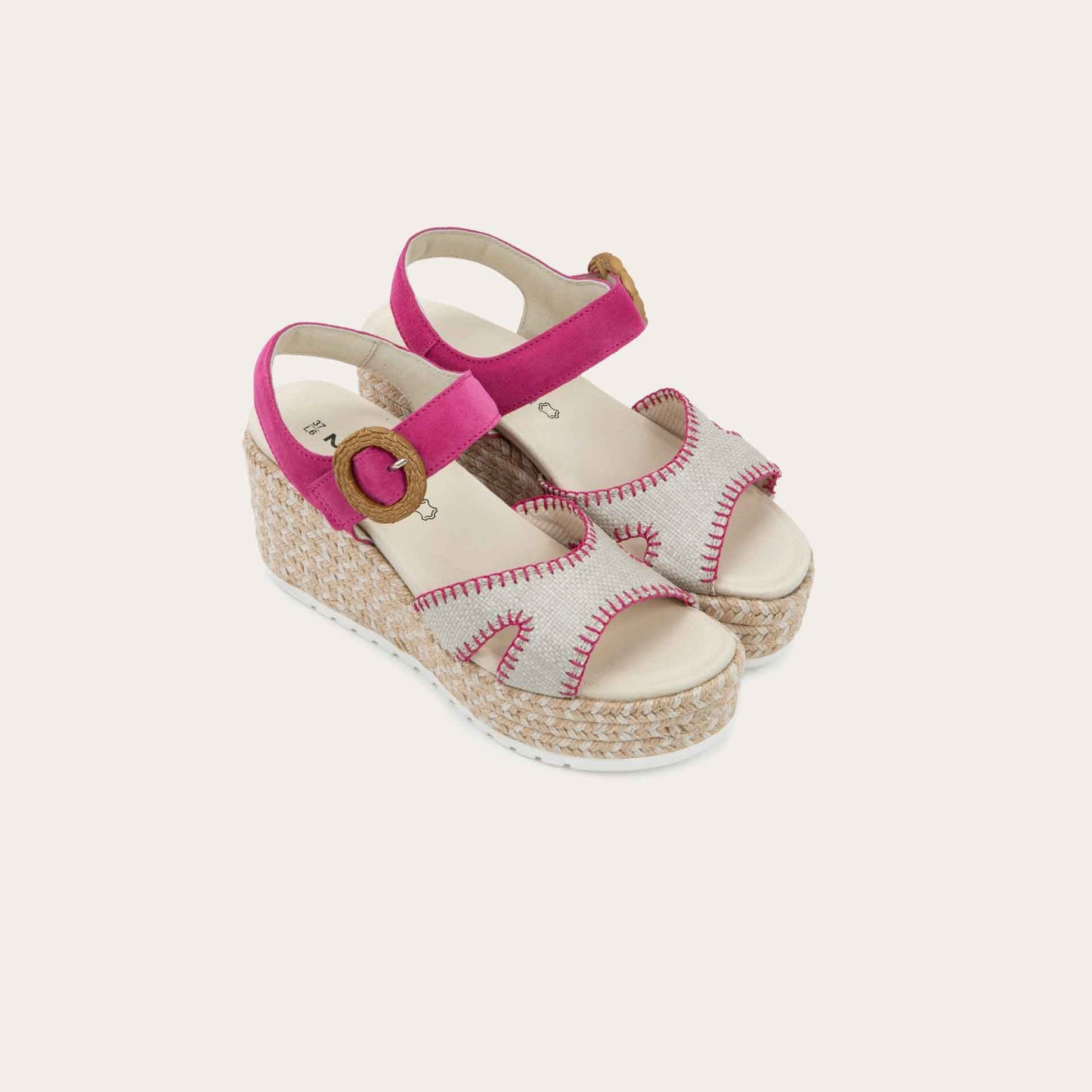 Pair of beige/pink wedge sandals with a woven platform and pink suede ankle strap, fastened by a circular buckle. 