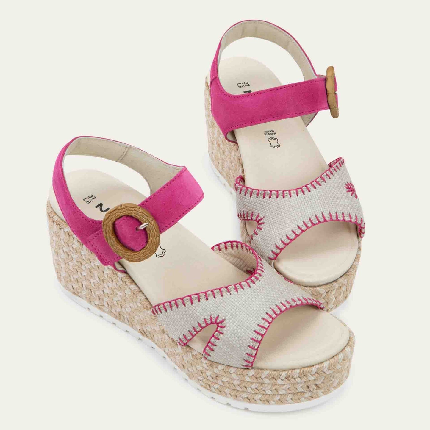 Pair of beige/pink wedge sandals with a woven platform and pink suede ankle strap, fastened by a circular buckle. 