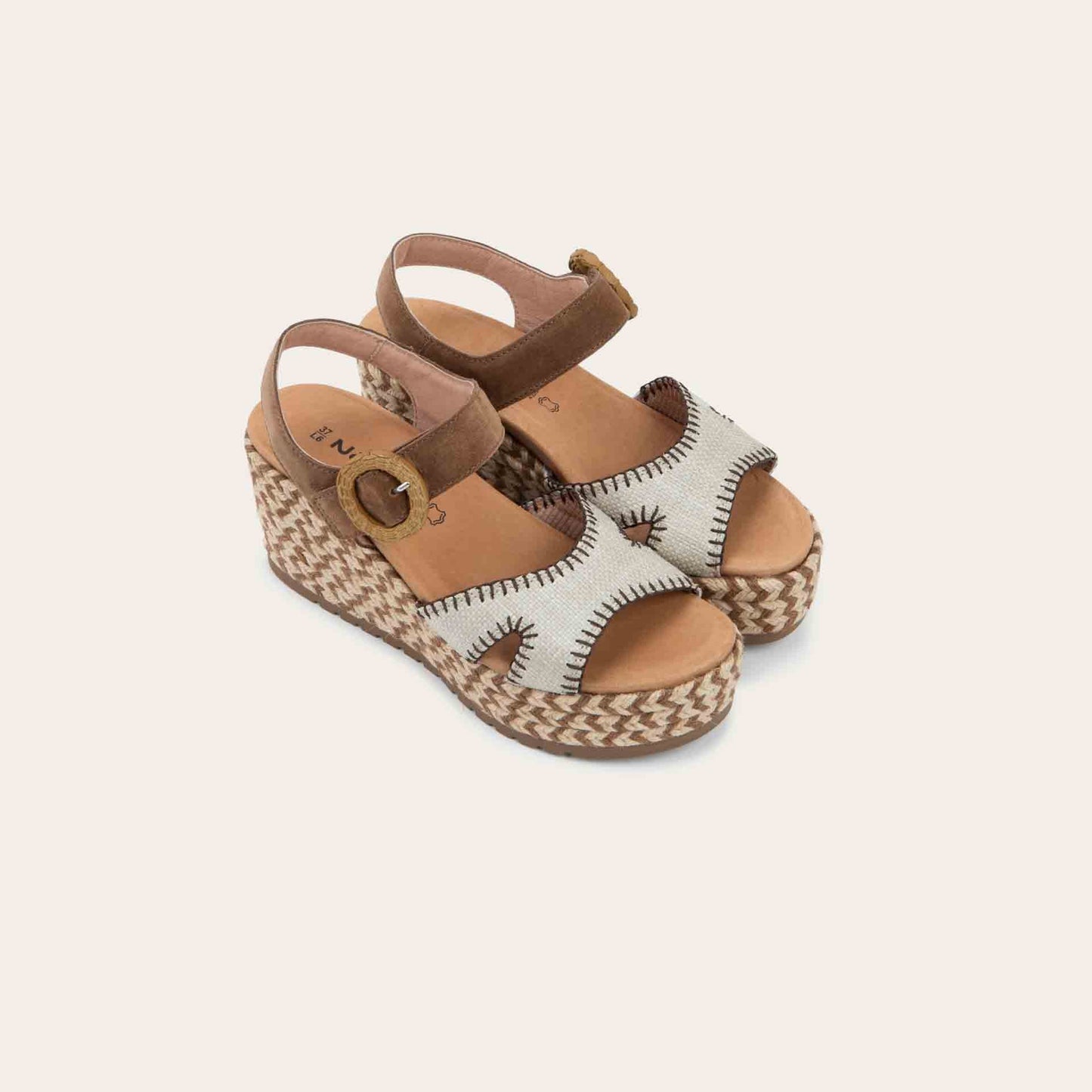 Pair of beige/brown wedge sandals with a woven platform and brown suede ankle strap, fastened by a circular buckle. 