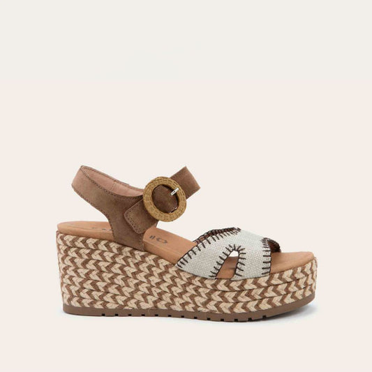 Profile view of a beige/brown wedge sandal with a woven platform and brown suede ankle strap, fastened by a circular buckle. 