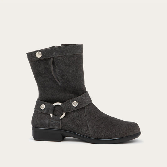 Profile view of a black suede mid-calf boot with decorative t-strap and buckle, side zipper, rounded toe, and low stacked heel
