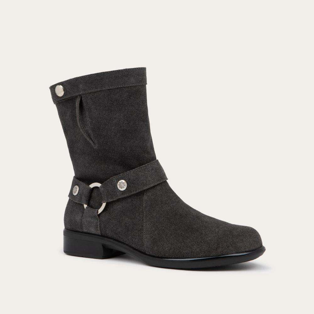 Angled profile view of a black suede mid-calf boot with decorative t-strap and buckle, side zipper, rounded toe, and low stacked heel
