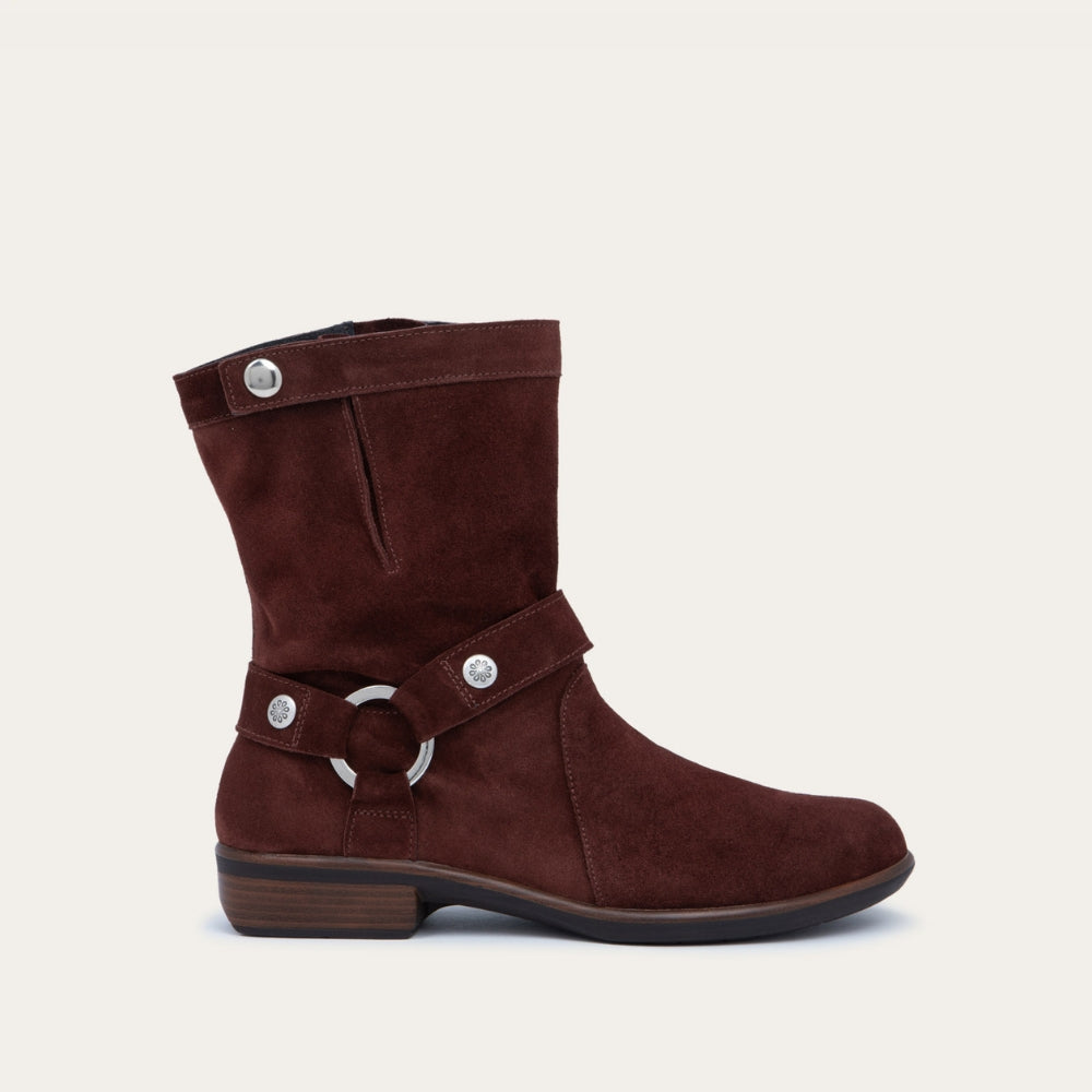 Profile view of a violet suede mid-calf boot with decorative t-strap and buckle, side zipper, rounded toe, and low stacked heel