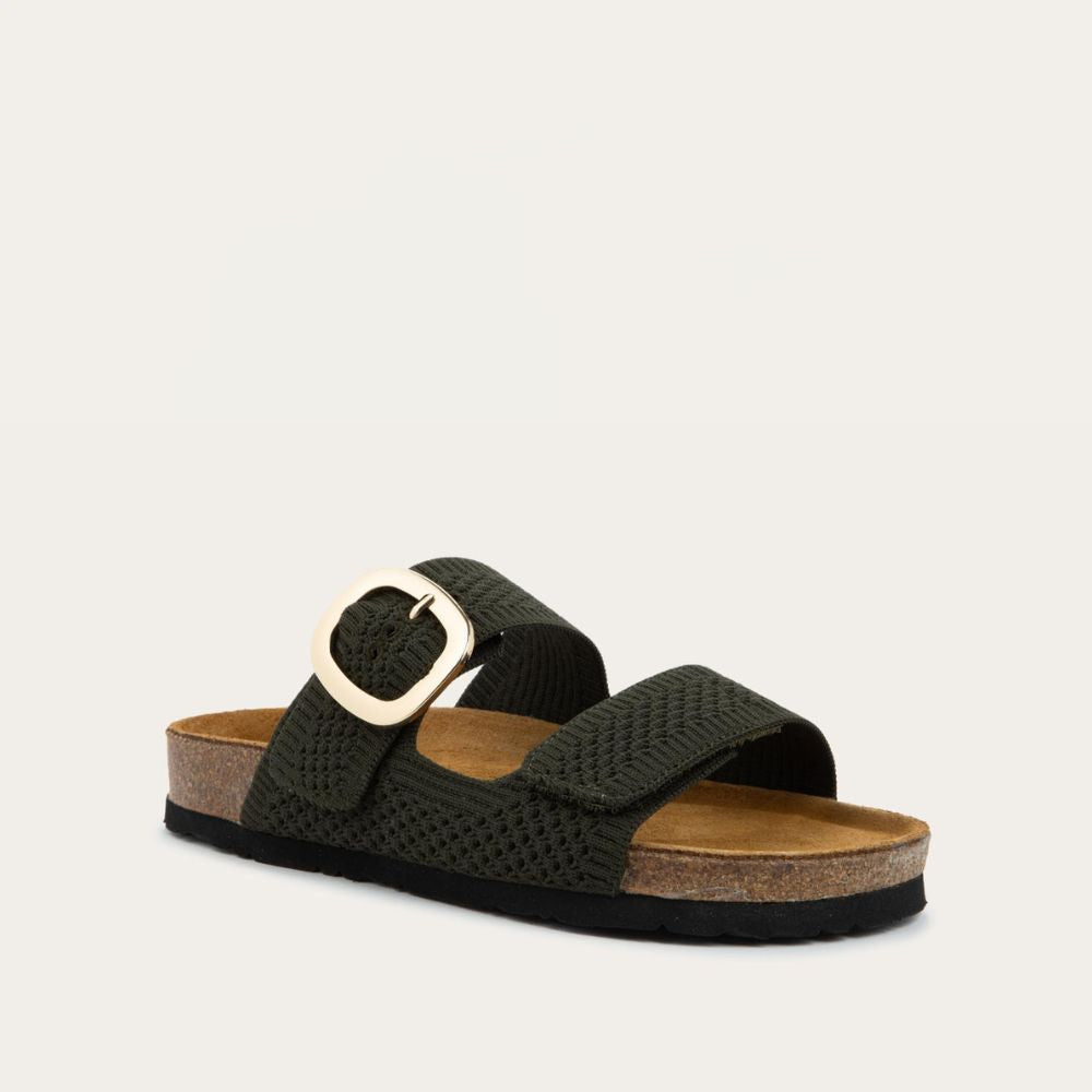 Angled profile view of a blue slip-on sandal with two adjustable knit straps and a large gold buckle. It has a cork footbed and a black sole.