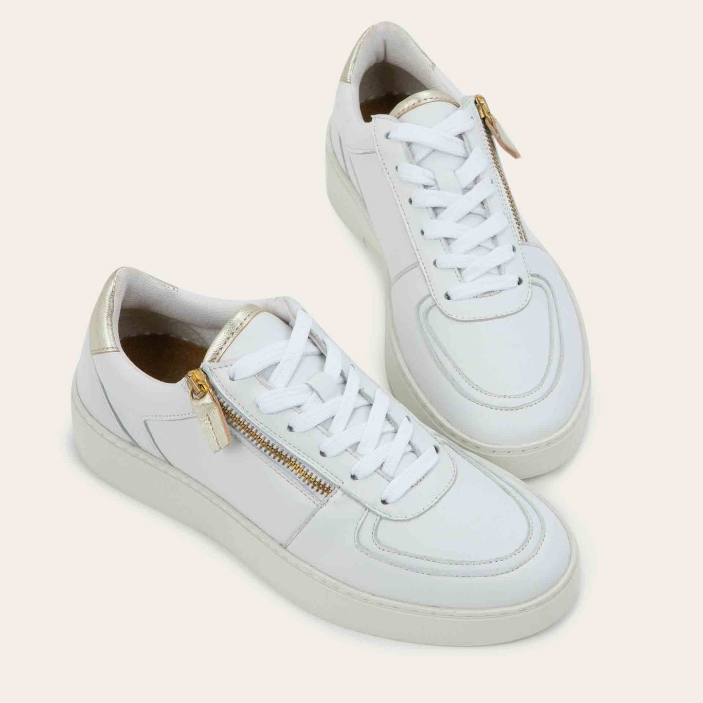 Pair of multicolored white and gold sneakers with laces and a side zipper.
