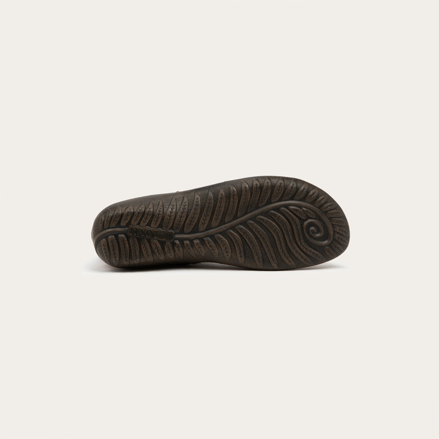Bottom view of a brown boot featuring an accent strap with round buckle in the back of the shoe on a dark sole.