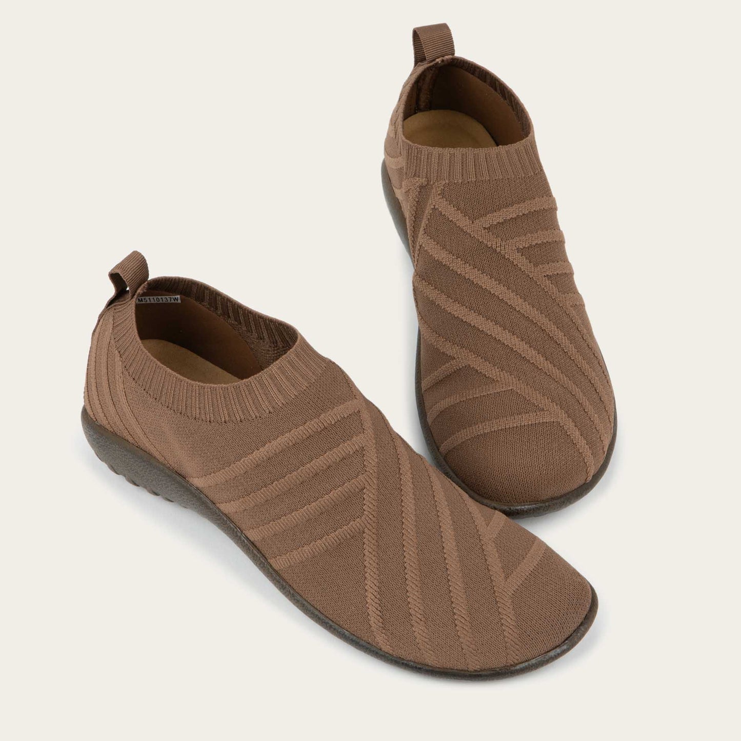 A pair of brown knit slip-on shoes on a gray sole