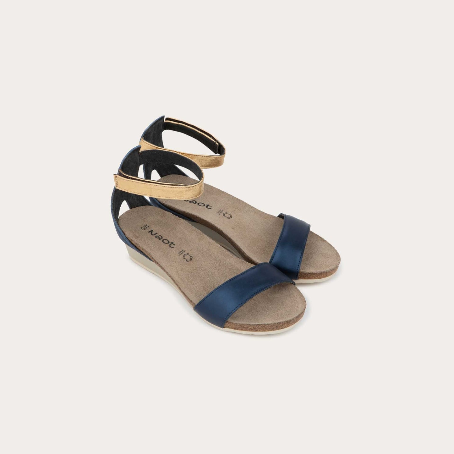 Pair of blue wedge sandals with cork sole, featuring an open toe and metallic gold ankle strap.