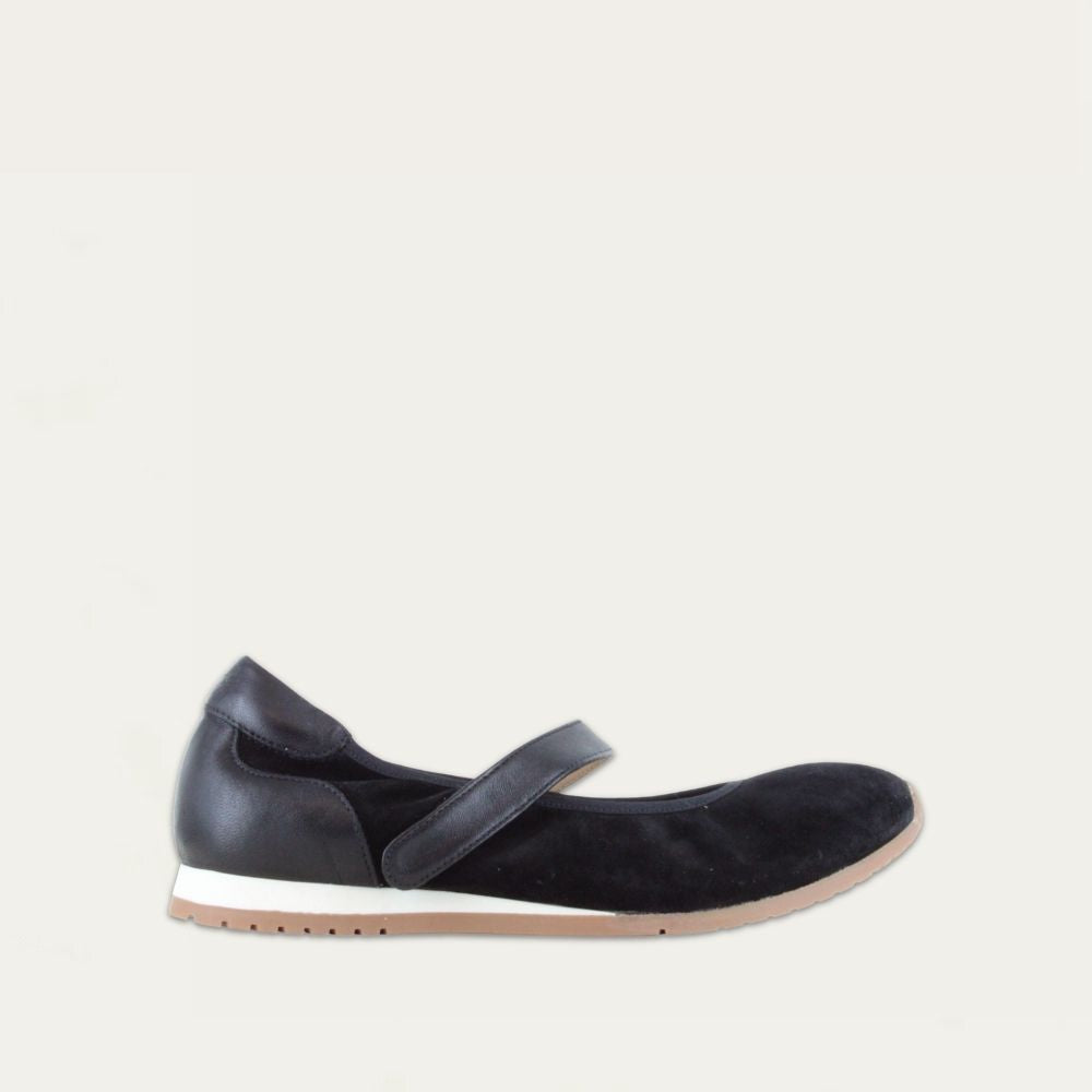 Profile view of a black leather mary jane on a low white and beige sole. 