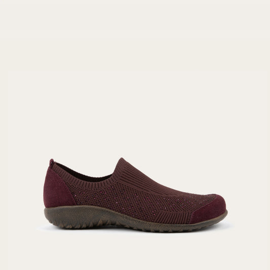 Profile view of a purple knit slip on shoe with rivet accents throughout.