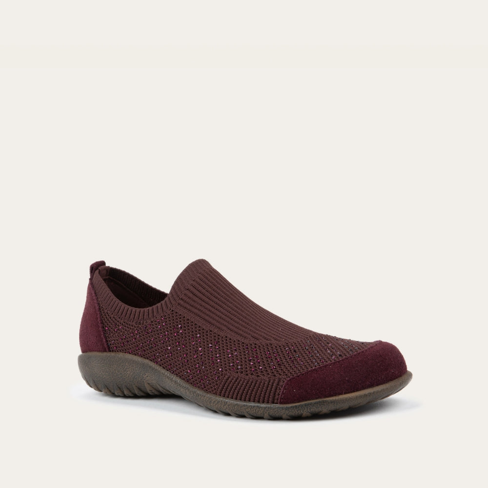 Angled profile view of a purple knit slip on shoe with rivet accents throughout.