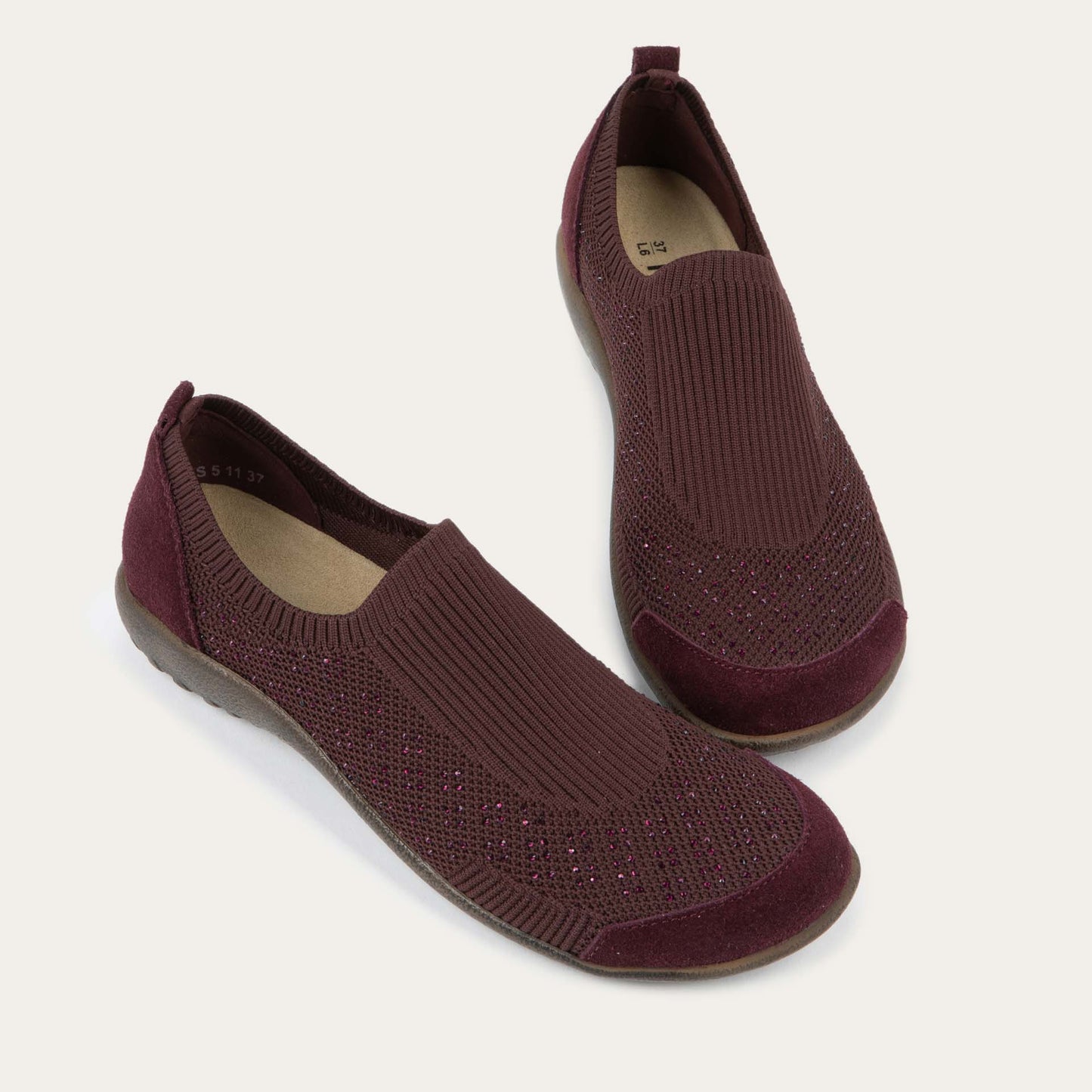 Pair of purple knit slip on shoes with rivet accents throughout.