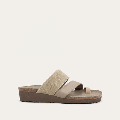 Profile view of beige, multi-strap, sling-back sandal with a cork footbed.