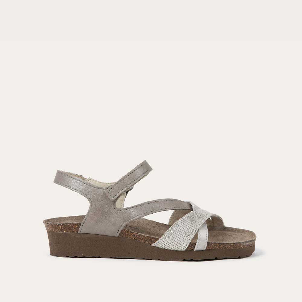 Profile view of a gray open-toe sandal with a cork wedge sole. Features leather and suede straps crossing over the front and a back strap with Velcro closure. 