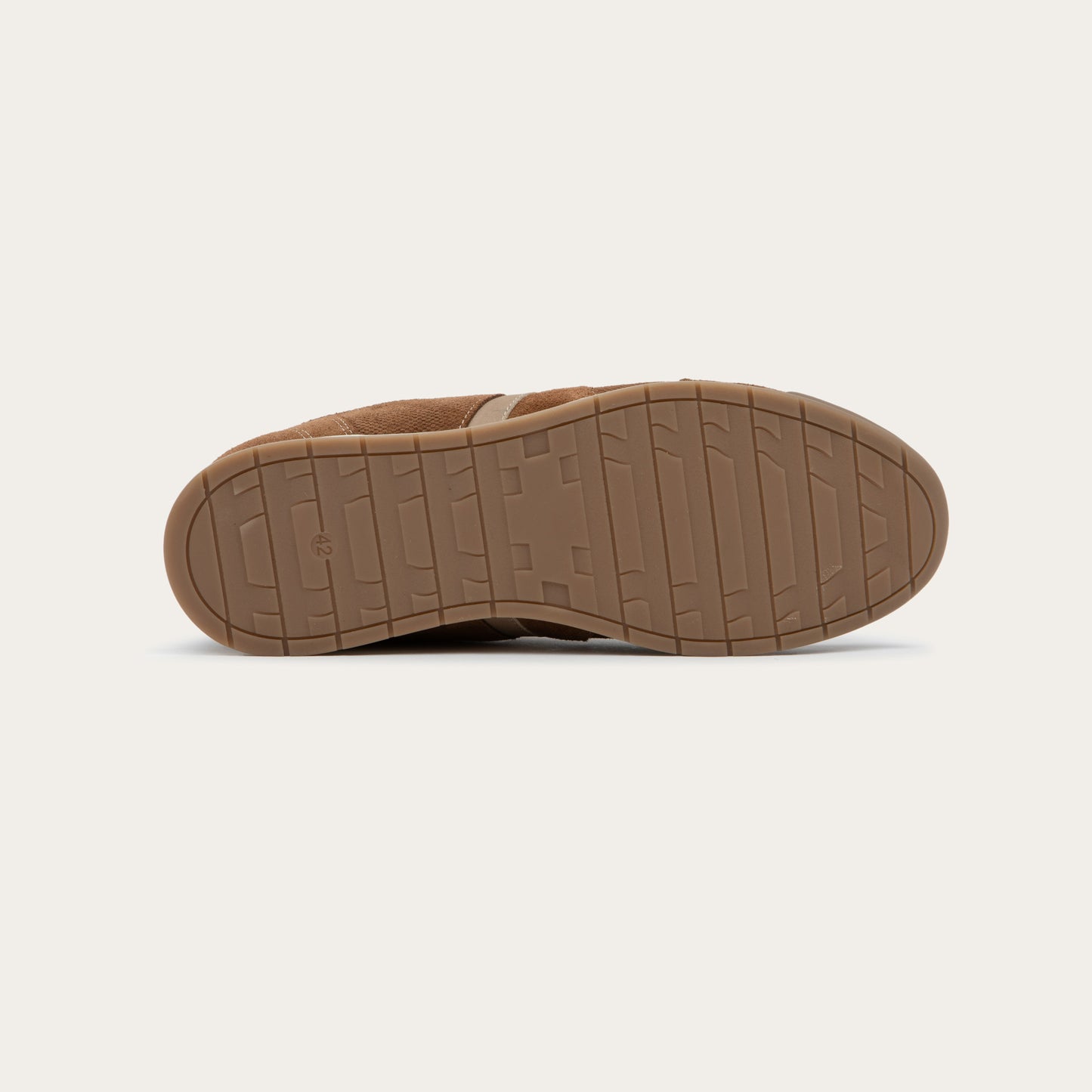 Bottom view of a brown and beige sneaker on a brown sole.